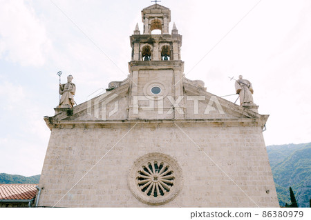 Church of St. Nicholas with statues on the roof and a rose window on the wall in Prcanj Church of St. Nicholas with statues on the roof and a rose window on the wall in Prcanj 86380979