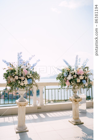 Lush bouquets of flowers in stone vases stand on the observation deck overlooking the sea 86381194
