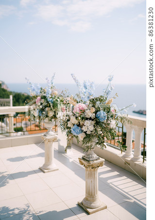 Bouquets of flowers stand on a terrace overlooking the sea 86381230