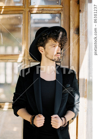 Young man in a black hat on the background of a wooden window 86381237