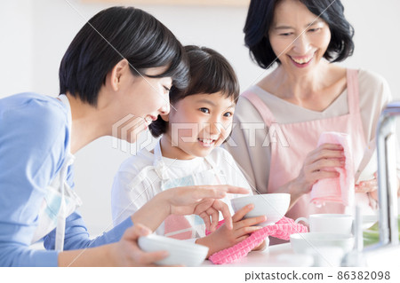 Three generation family mom and grandma and a girl wiping dishes Three generation family mom and grandma and a girl wiping dishes 86382098