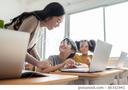 Happy Smiling Asian female teacher is teaching and advice her Asian boy learning on laptop. 86382941
