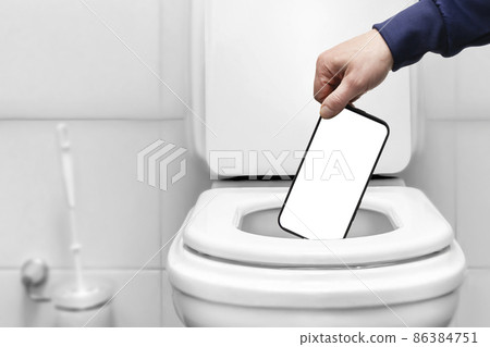 the hand throws the phone with an empty white screen into the toilet or trash can. mockup layout for labels the hand throws the phone with an empty white screen into the toilet or trash can. mockup layout for labels 86384751
