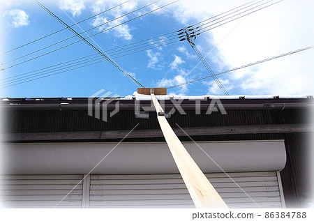 [HDR 風格] 使用自製的除雪工具清除屋頂上的雪的場景，刀片附在長桿的尖端。 86384788