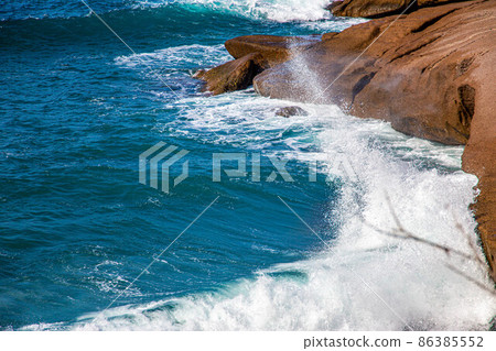 The waves of the Atlantic Ocean crash on rocks with splashes in Tenerife The waves of the Atlantic Ocean crash on rocks with splashes in Tenerife 86385552