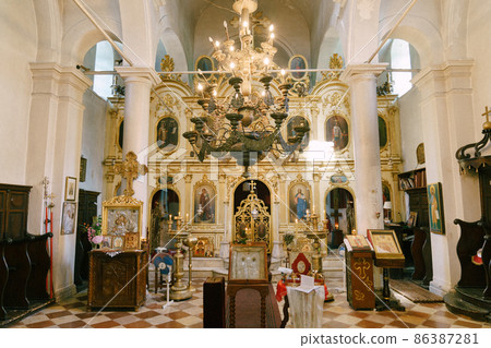 Gold chandelier hangs against the background of the altar in the church with white columns Gold chandelier hangs against the background of the altar in the church with white columns 86387281