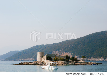 Motor yacht sails to the fortress on the island of Otocic Gospa. Montenegro 86387392