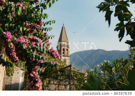 Bell tower of the Church of St. Nicholas against the background of mountains. Perast, Montenegro Bell tower of the Church of St. Nicholas against the background of mountains. Perast, Montenegro 86387639