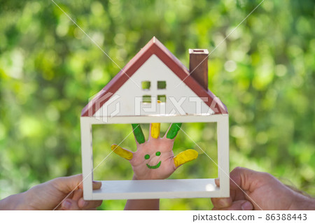 Family holding house in hands against spring green background 86388443