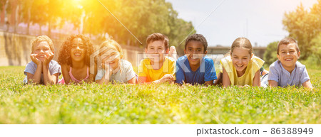 Happy team of friends children resting on grass at sunny day Happy team of friends children resting on grass at sunny day 86388949