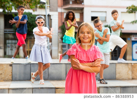 Positive girl dancing modern choreography with group of tweenagers outdoors Positive girl dancing modern choreography with group of tweenagers outdoors 86388953