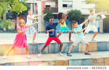 Group of tweenagers performing street dance choreography outdoors Group of tweenagers performing street dance choreography outdoors 86389228