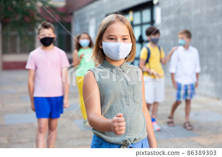Tween girl in protective mask walking along city street 86389303
