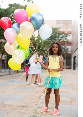 Full length portrait of happy african american preteen girl with balloons Full length portrait of happy african american preteen girl with balloons 86389443