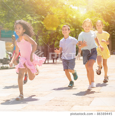 Team of positive kids running in race in the street and laughing 86389445