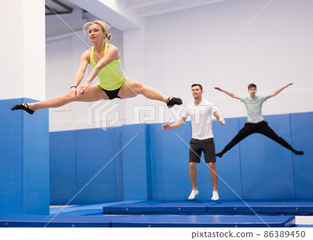 Woman practicing side split on trampoline 86389450