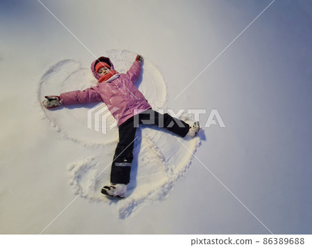Little girl lying in snow and making angel top view 86389688