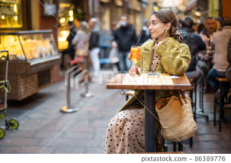 Woman with a cocktail at outdoor bar or restaurant in Bologna city 86389776