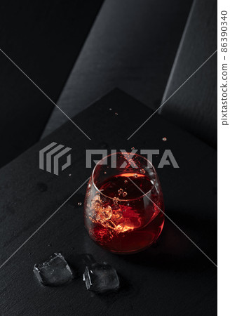Ice cubes fall into a glass of whiskey. Ice cubes fall into a glass of whiskey. 86390340