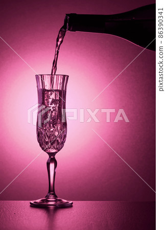 Sparkling wine is poured from a bottle into a glass. Sparkling wine is poured from a bottle into a glass. 86390341
