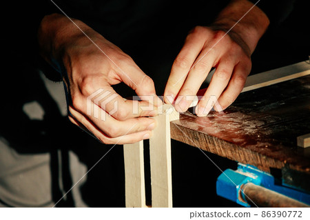 Carpenter at workbench nails down small wooden box. Hands of worker with old axe. Authentic workflow Carpenter at workbench nails down small wooden box. Hands of worker with old axe. Authentic workflow 86390772