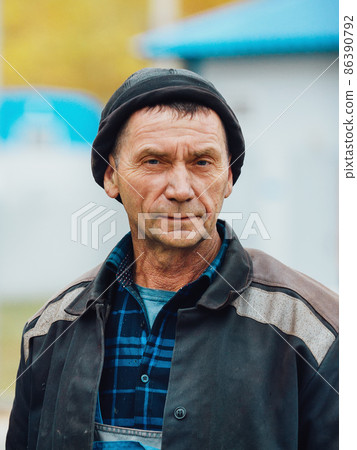Chest-high portrait of working man. Genuine tired worker builder in work clothes stands on street 86390792