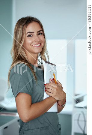 Smiling female doctor in hospital corridor. Patients consultation. Female Doctor with arms crossed 86392115