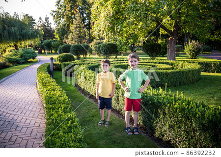 Two siblings playing at beautiful green park together. Happy family of two best friend brothers standing together. Brothers play outdoor background summer 86392232