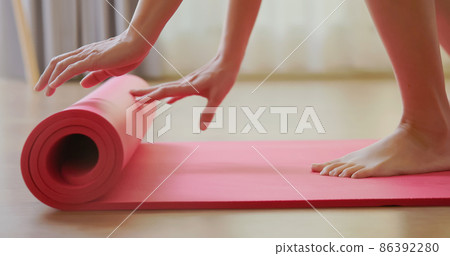 Woman rolling pink yoga mat 86392280