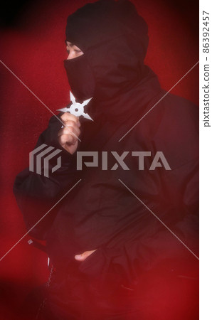 Asian Man Wearing Ninja Costume and holding Ninja Weapons 86392457