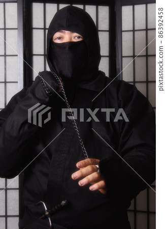 Asian Man Wearing Ninja Costume and holding Ninja Weapons 86392458