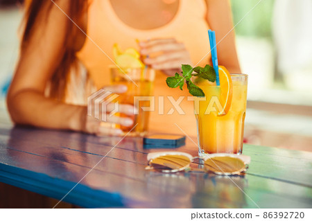 Cocktail in woman hand on the open terrace in bar during summer time Cocktail in woman hand on the open terrace in bar during summer time 86392720