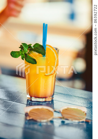 Cocktail in woman hand on the open terrace in bar during summer time Cocktail in woman hand on the open terrace in bar during summer time 86392722