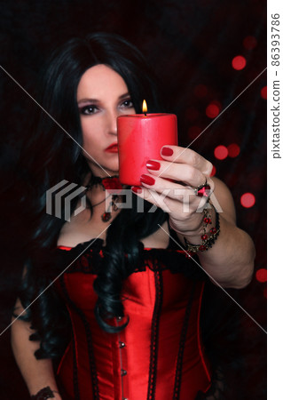 Woman in Red Corset holding Candle With Red Bokeh Background 86393786