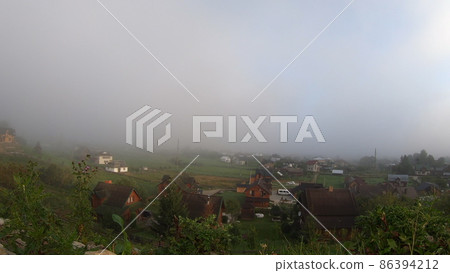 Morning fog dissipates in the mountains Carpathians. 86394212