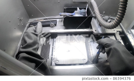 Male worker in rubber glove cleans printing platform inside 3d printer for metal 86394376