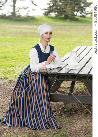 Latvian woman in traditional clothing with milk glass on nature 86394986