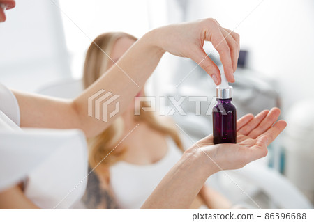 Female beautician hands holding bottle of vitamin serum Female beautician hands holding bottle of vitamin serum 86396688