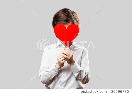 Boy covering his face with red st valentines heart 86396780