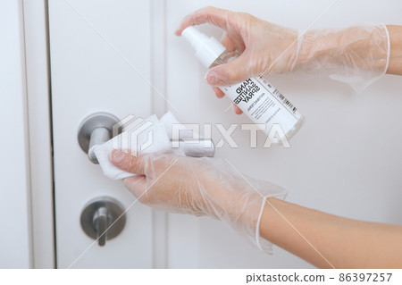 Cleaning door handles with wet wipe and white gloves. Woman hand using towel for cleaning home room door link. Sanitize surfaces prevention in hospital and public spaces against corona virus. Cleaning door handles with wet wipe and white gloves. Woman hand using towel for cleaning home room door link. Sanitize surfaces prevention in hospital and public spaces against corona virus. 86397257
