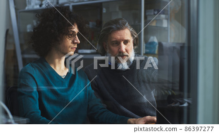Male designers discussing data on computer Male designers discussing data on computer 86397277