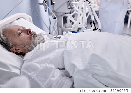 Sick Caucasian Man With Endotracheal Tube In Mouth Lying On Medical Couch In Hospital Sick Caucasian Man With Endotracheal Tube In Mouth Lying On Medical Couch In Hospital 86399985