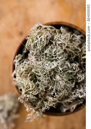 Dried Icelandic moss in a wooden mug, top view, close-up 86400095
