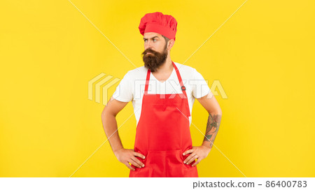 Confident man in red toque and apron looking aside with arms akimbo yellow background, chef Confident man in red toque and apron looking aside with arms akimbo yellow background, chef 86400783