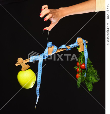 Female hand holds hanger with tape and food on tips Female hand holds hanger with tape and food on tips 86401359