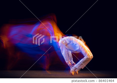 Sportive, emotional man, dancer dancing hip-hop isolated on dark background in mixed neon light. Youth culture, hip-hop, movement, style and fashion, action. 86401464