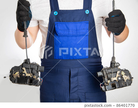 An auto electrician holds central car door locks in his hands. The concept of repair and replacement of electricians at a car service. Close-up An auto electrician holds central car door locks in his hands. The concept of repair and replacement of electricians at a car service. Close-up 86401770
