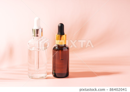 Dark and light glass bottles with pipettes on pink background Dark and light glass bottles with pipettes on pink background 86402041
