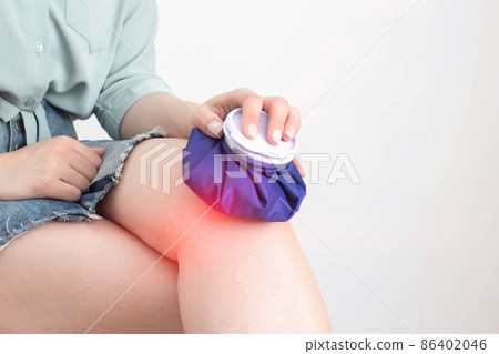 The girl applies a medical bag with cold to the injured knee for diseases of bursitis and sprains. Cold Knee Treatment, rheumatology The girl applies a medical bag with cold to the injured knee for diseases of bursitis and sprains. Cold Knee Treatment, rheumatology 86402046