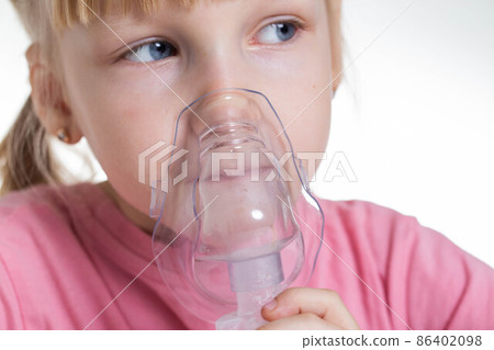 A 5-year-old girl breathes into an inhaler to dilute sputum in case of lung diseases. Treatment of cough in children. Nebulizer therapy A 5-year-old girl breathes into an inhaler to dilute sputum in case of lung diseases. Treatment of cough in children. Nebulizer therapy 86402098